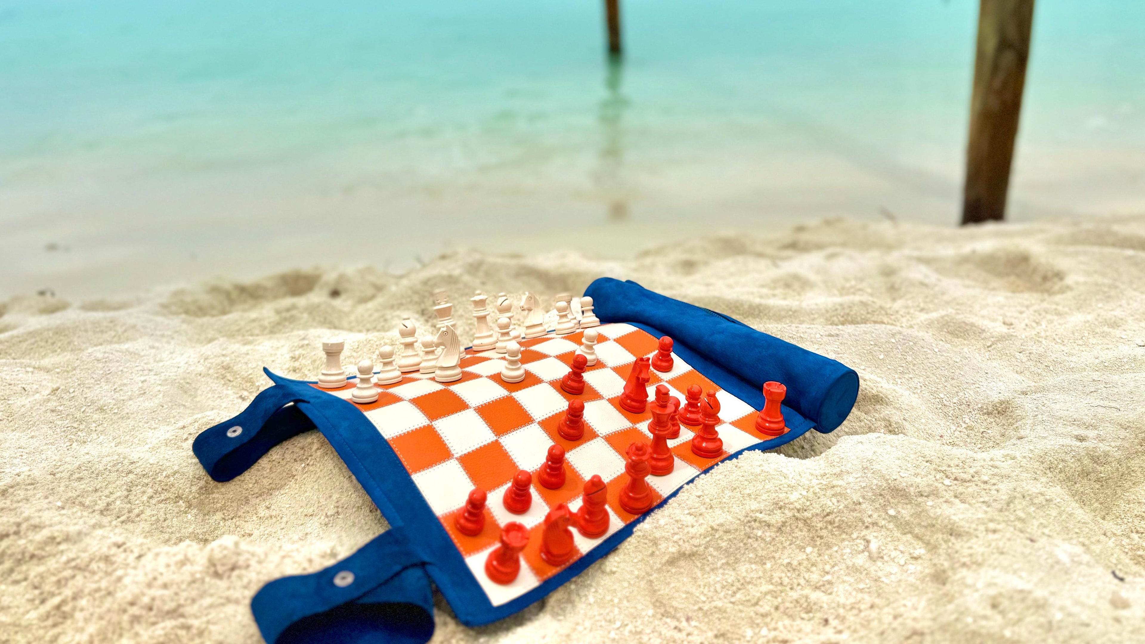 Load video: Luxury leather travel chess set on a sandy beach demonstrating portable handcrafted chess for outdoor and luxury travel.