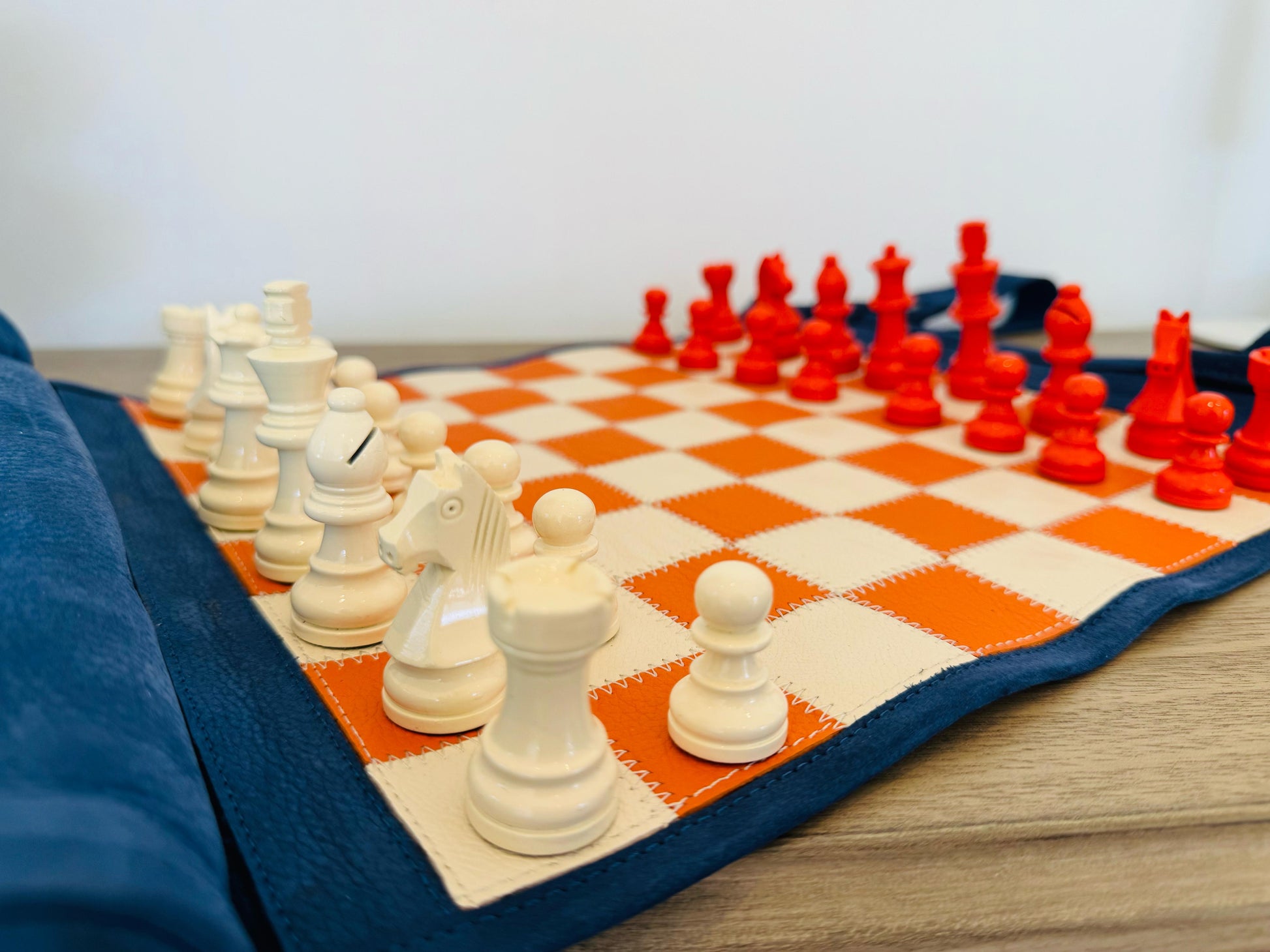 Close-up of orange magnetic chess pieces on the handcrafted leather board