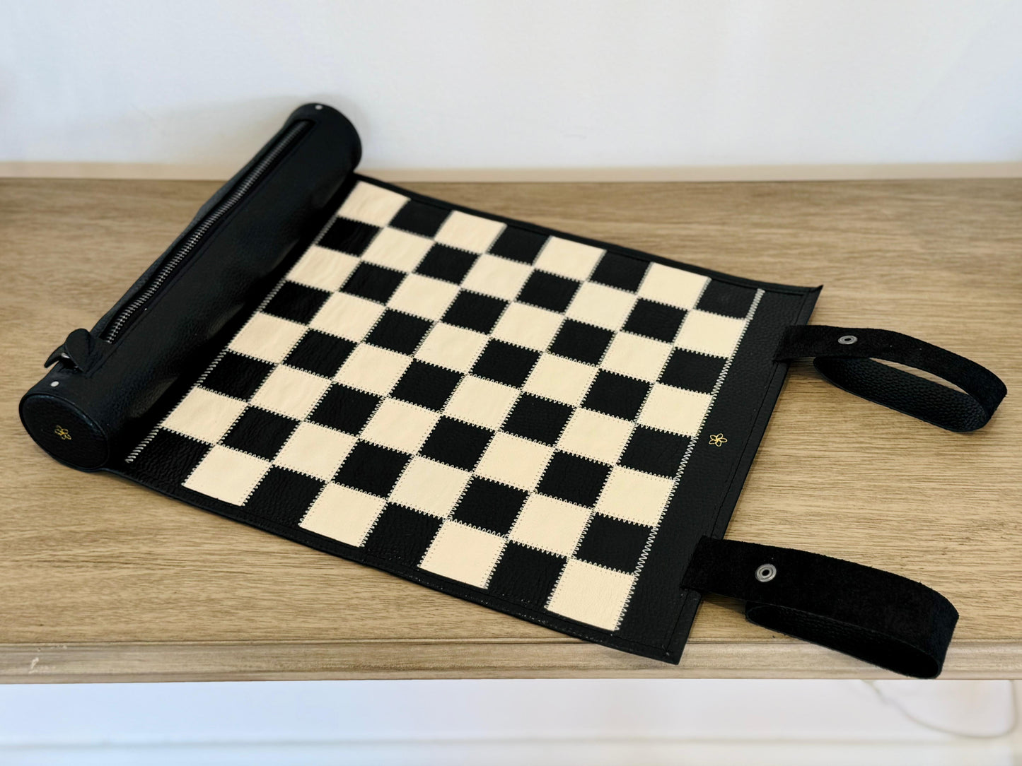 Luxury roll-up leather chess board in black with magnetic wooden chess pieces arranged for play
