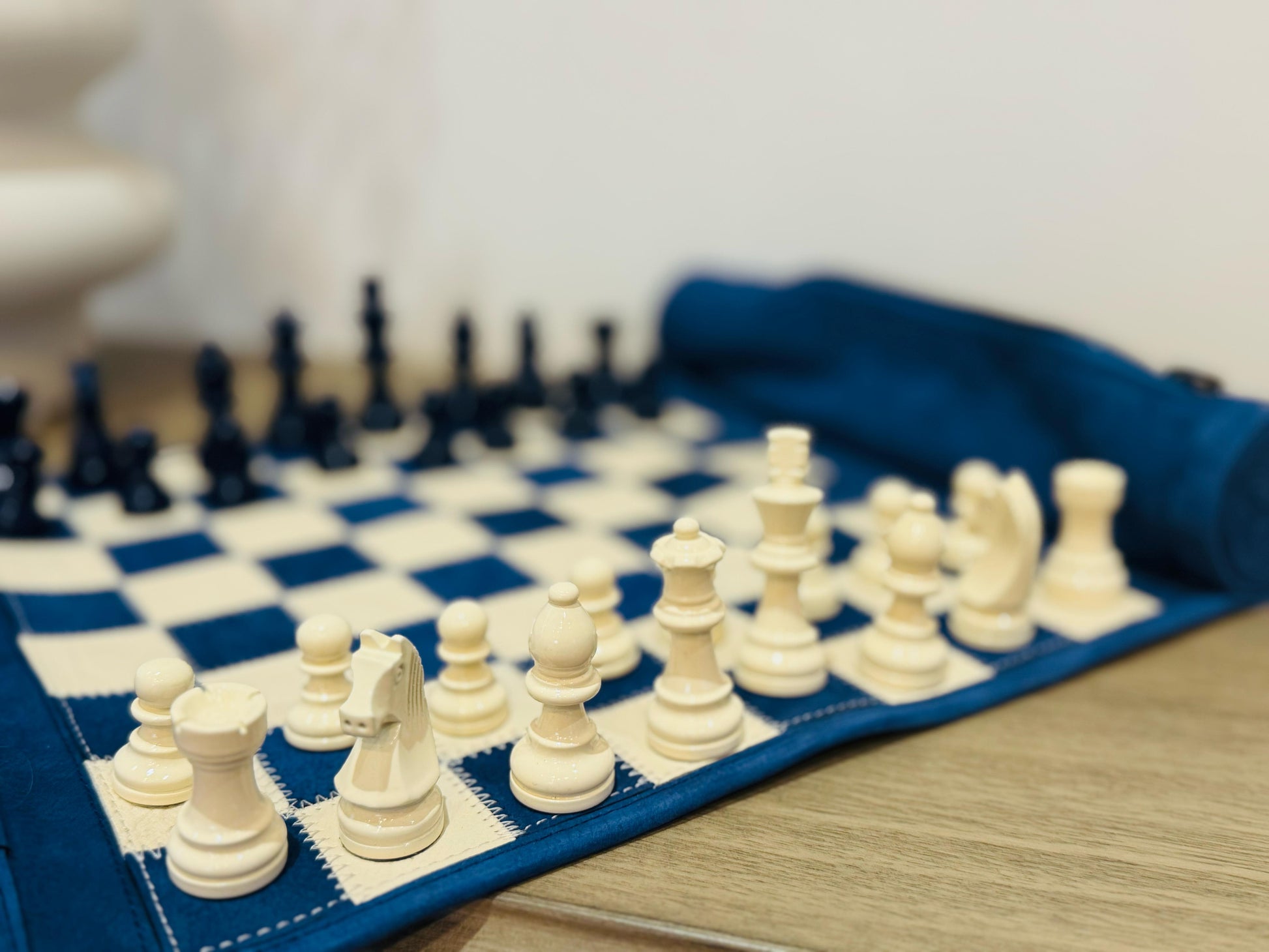 Close-up of navy and ivory magnetic chess pieces on the Ocean Blue leather board