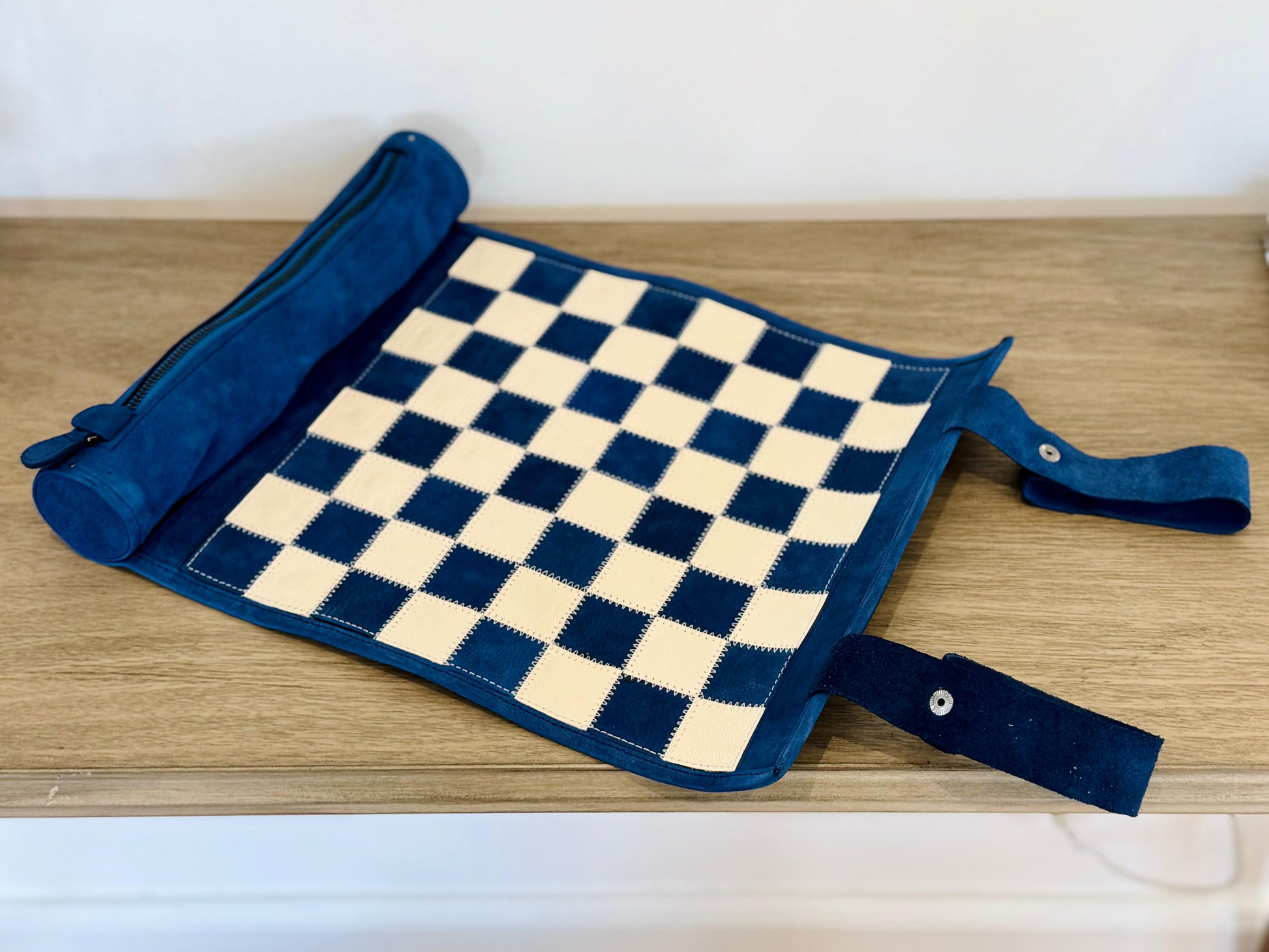 Folded Ocean Blue leather chessboard with carrying straps for compact travel
